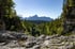 Felsige Flusslandschaft mit Wald, Bergen und einer Aussichtsplattform unter klarem, blauem Himmel.