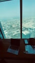 Laptop auf Holztisch vor einer Glasfensterfront mit Blick auf eine Skyline.
