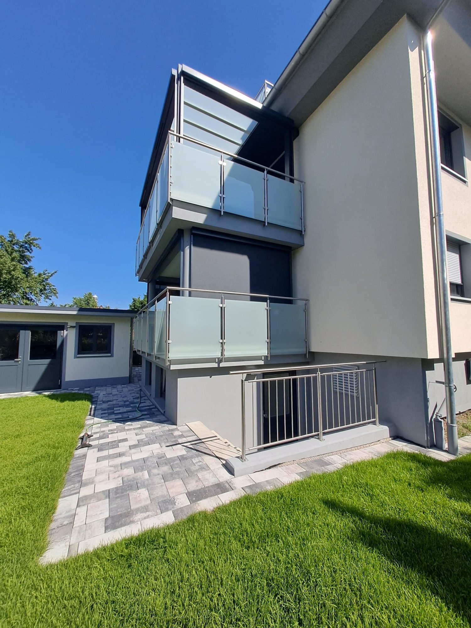 Wohnhaus mit Glas-Balkongeländern aus Edelstahl und Geländer am Kellerabgang