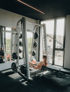 Frau in Sporthosen und Sport-BH macht Kniebeugen mit Langhantel im Fitnessstudio.