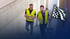 Dirk Abel und Dominik Walter in Warnweste gehen durch den Rohbau, daneben eine Zielflagge