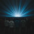 Silhouetted crowd facing a stage with blue light beams fanning overhead