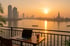 Sonnenuntergang über dem Fluss in Bangkok mit Laptop und Eiskaffee auf einem Balkontisch.