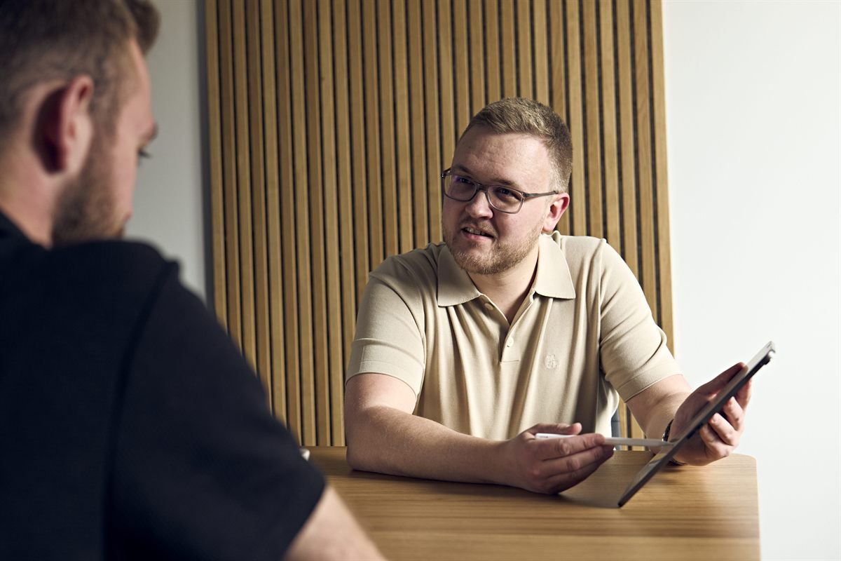 Versicherungsmakler im Beratungsgespräch mit einem Kunden am Besprechungstisch