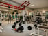 Moderner Fitnessraum mit Hantelstationen, Kraftgeräten, einer roten Hangelleiter und dem Schild Stronger Than Yesterday.