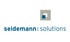 Logo von seidemann: solutions mit einem quadratischen Symbol über dem blauen Schriftzug auf schwarzem Hintergrund.