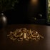 Goldkette, Ringe und Ohrringe auf einem dunklen Holztisch, im Hintergrund eine Vase mit Pflanzen.