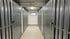Gang zwischen zwei Reihen von Selfstorage-Lagereinheiten mit kleinen Fenstern am Ende.