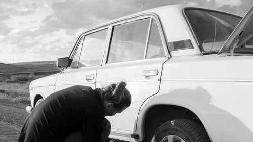 Driver changing a flat tire at the roadside in Cuyahoga Falls, Ohio