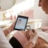 Kosmetikerin analysiert Gesichtshaut der Kundin mit Lupe und Tablet, das eine Hautkarte anzeigt.