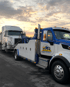 Towing Port Charlotte heavy-duty towing service recovering a semi truck with a heavy wrecker at sunset.