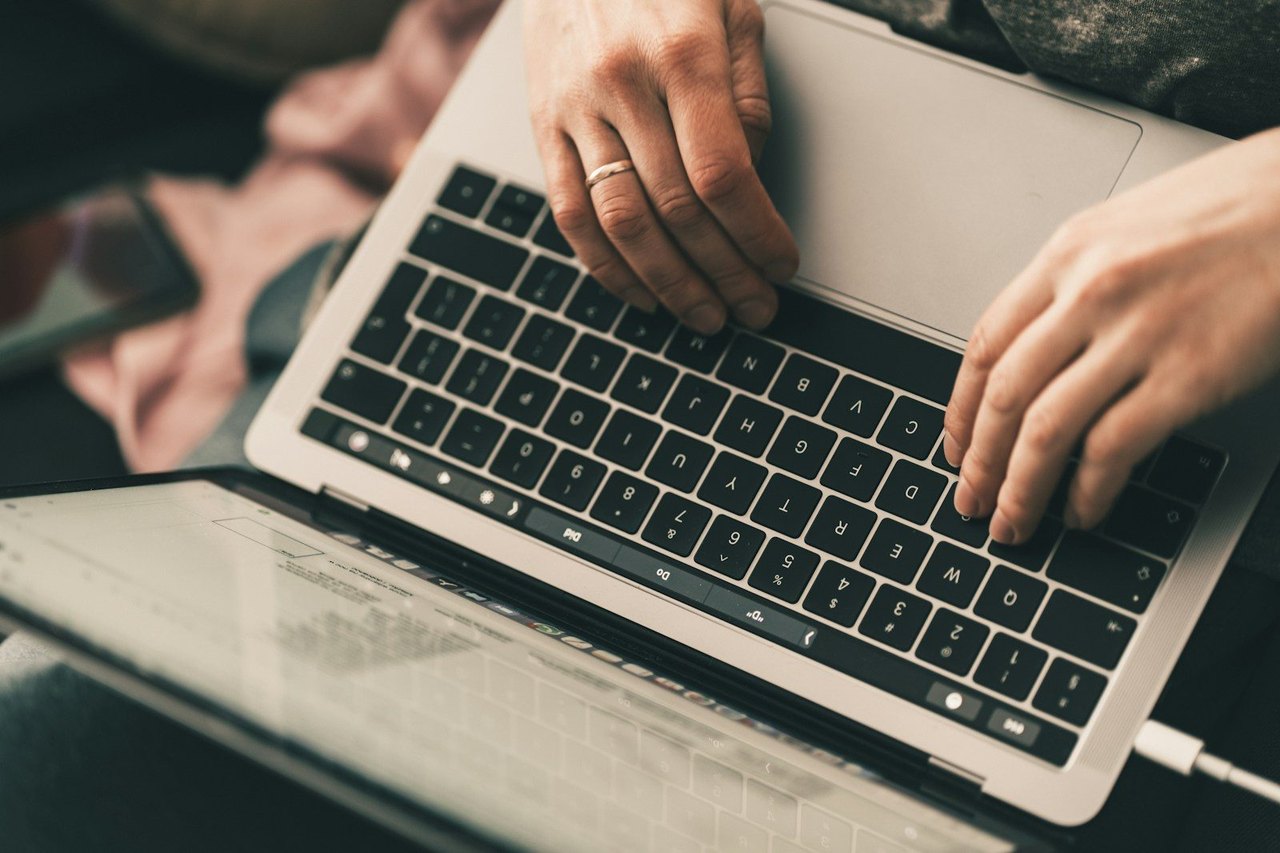 Zwei Hände tippen auf einem MacBook Pro