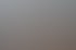 Eine lächelnde Frau mit blonden Haaren sitzt an einem Schreibtisch mit Kameras, Objektiven und einem Monitor.