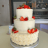 Dreistöckige Hochzeitstorte mit weißer Buttercreme und frischen Erdbeeren, auf einem weißen Kuchenständer.
