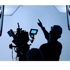 Eine Person zeigt auf eine beleuchtete Filmkulisse neben einer Videokamera.