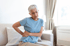 A woman sits and holds her back, experiencing pain.

