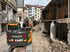 Ein Volvo-Bagger der Firma Becker steht auf einer Baustelle zwischen entkernten Gebäuden und Schutt.