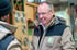 Lächelnder Mann mit Brille in beiger Jacke mit grünem K-Logo und Text „die tischlerei michael krüger“