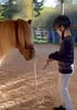 Ein Junge mit Helm und Brille hält ein Seil, das an einem Pony mit langem, hellem Fell befestigt ist.