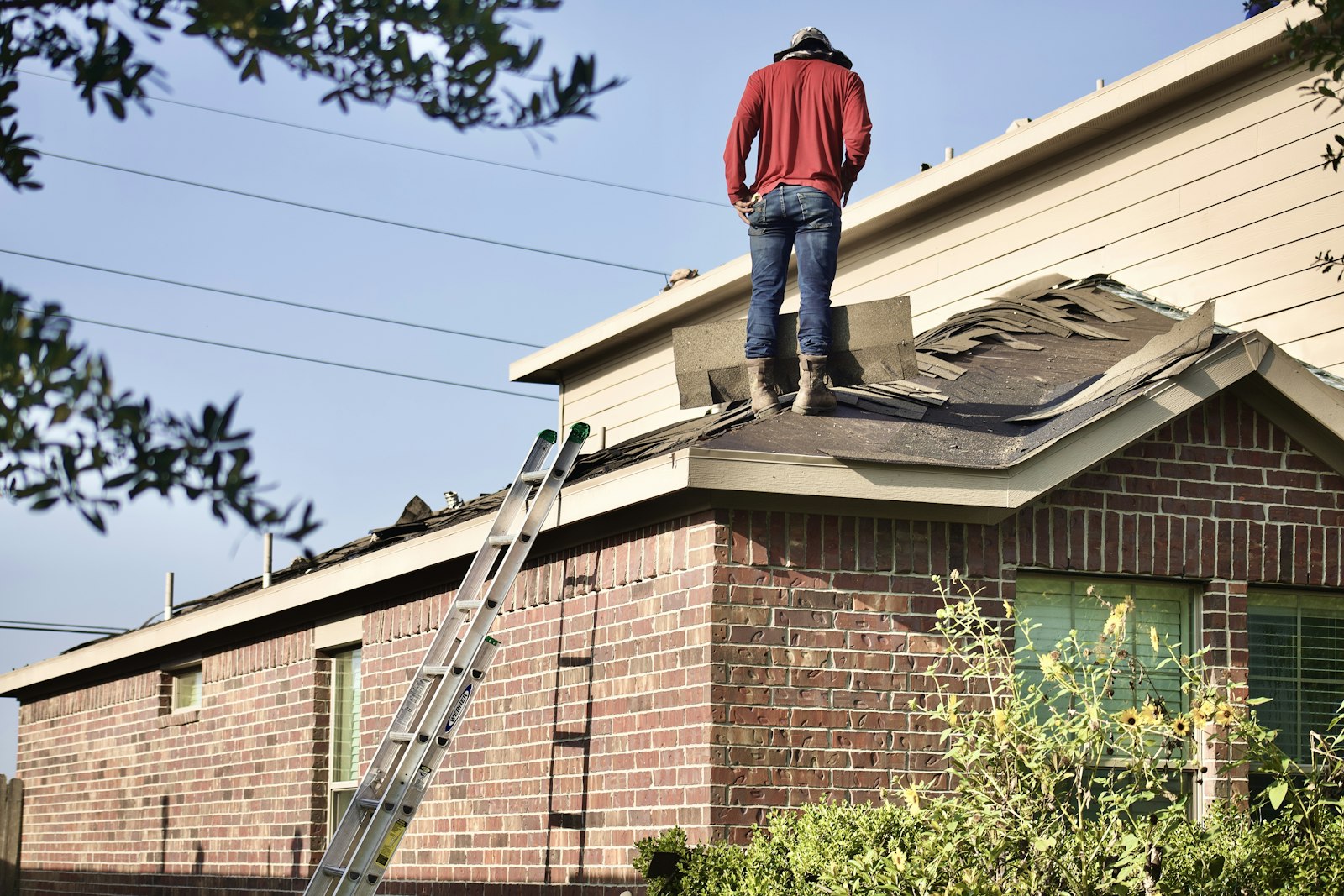 Roofer working on the roof of a brick home in Joshua, Texas