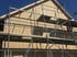 Neues Holzhaus mit vertikaler Holzverkleidung und Baugerüst davor.