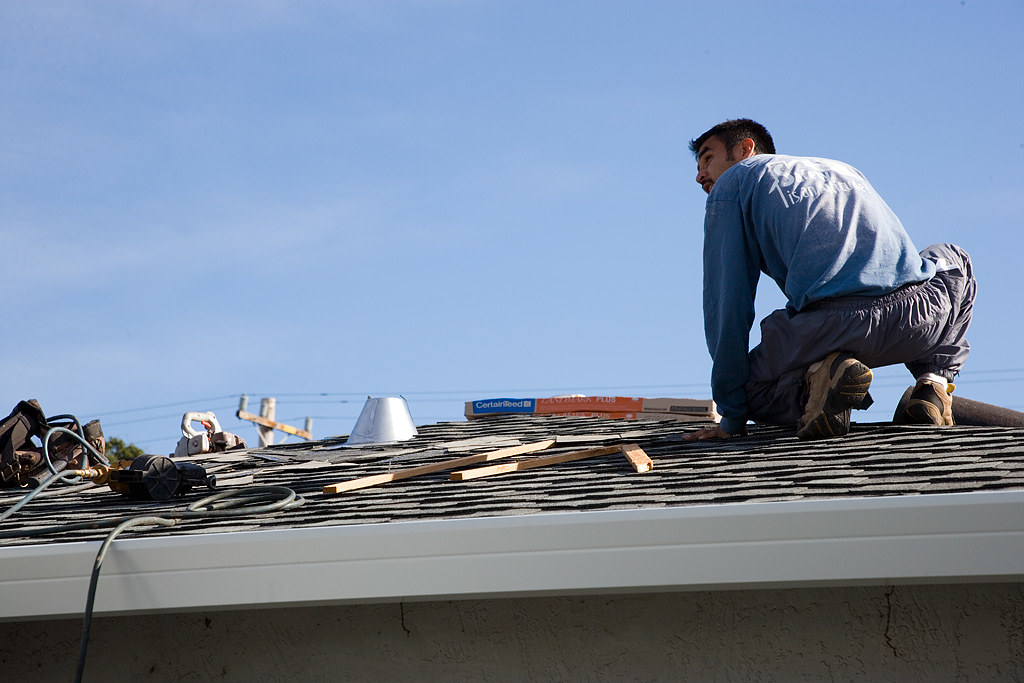 Roofer working along the ridge of a residential roof under a clear sky