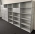 Modulares weißes Regalsystem mit Schubladen und offenen Fächern auf grauem Teppichboden.