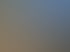 Ein Güterzug mit gelben und weißen Kesselwagen steht auf einem Gleis neben einem leeren Gleis unter blauem Himmel.