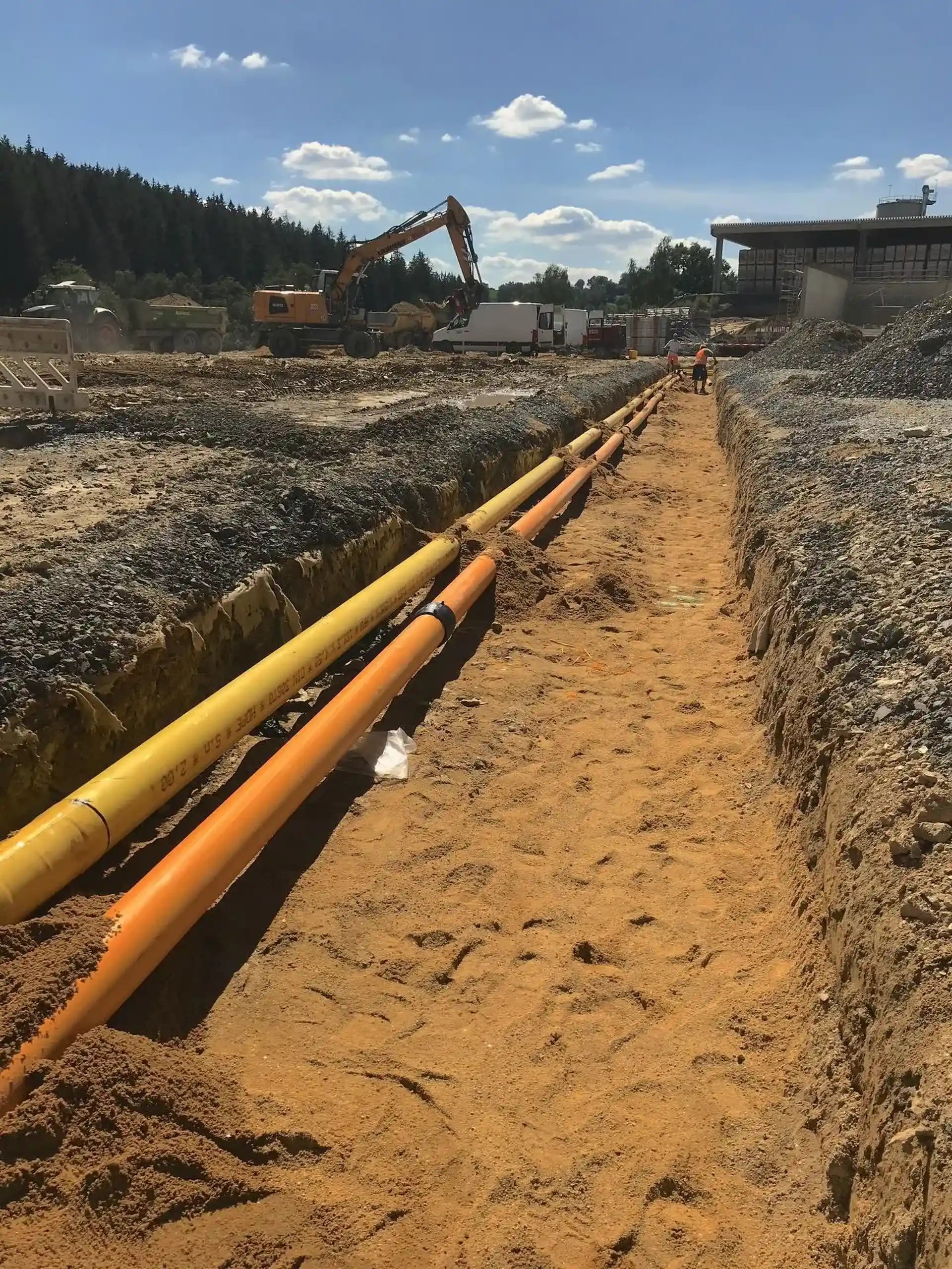 Gelbe und orangefarbene Wasserstoffrohre in einem Graben auf einer ASK-Baustelle.