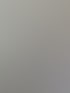 Ein weißes Klimagerät an einer hellgrauen Wand über einem Fenster mit Blick nach draußen.