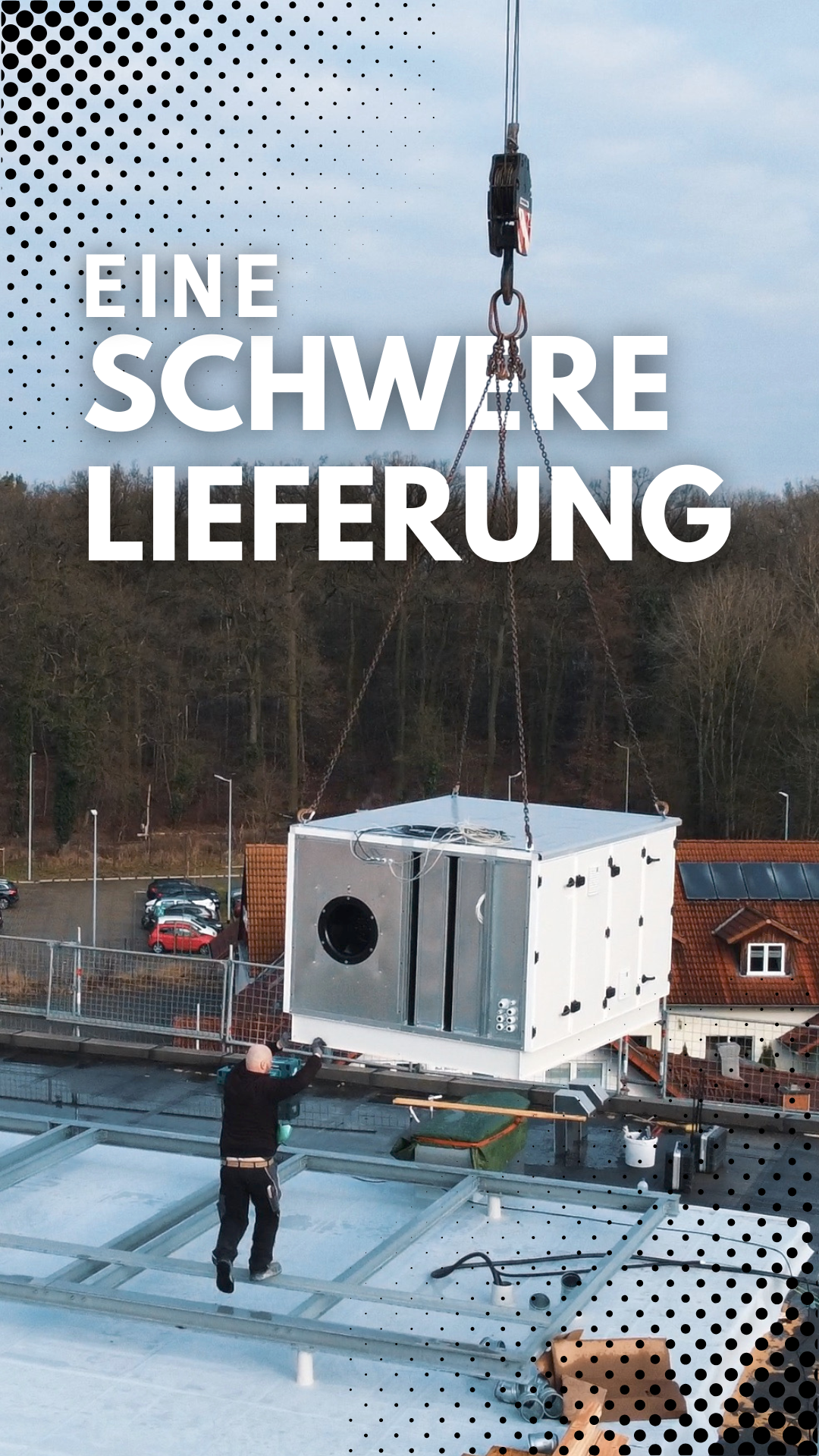 Ein Kran hebt eine große Klimaanlage auf ein Dach, während ein Arbeiter sie positioniert. Text: SCHWERE LIEFERUNG KRAL GMBH.