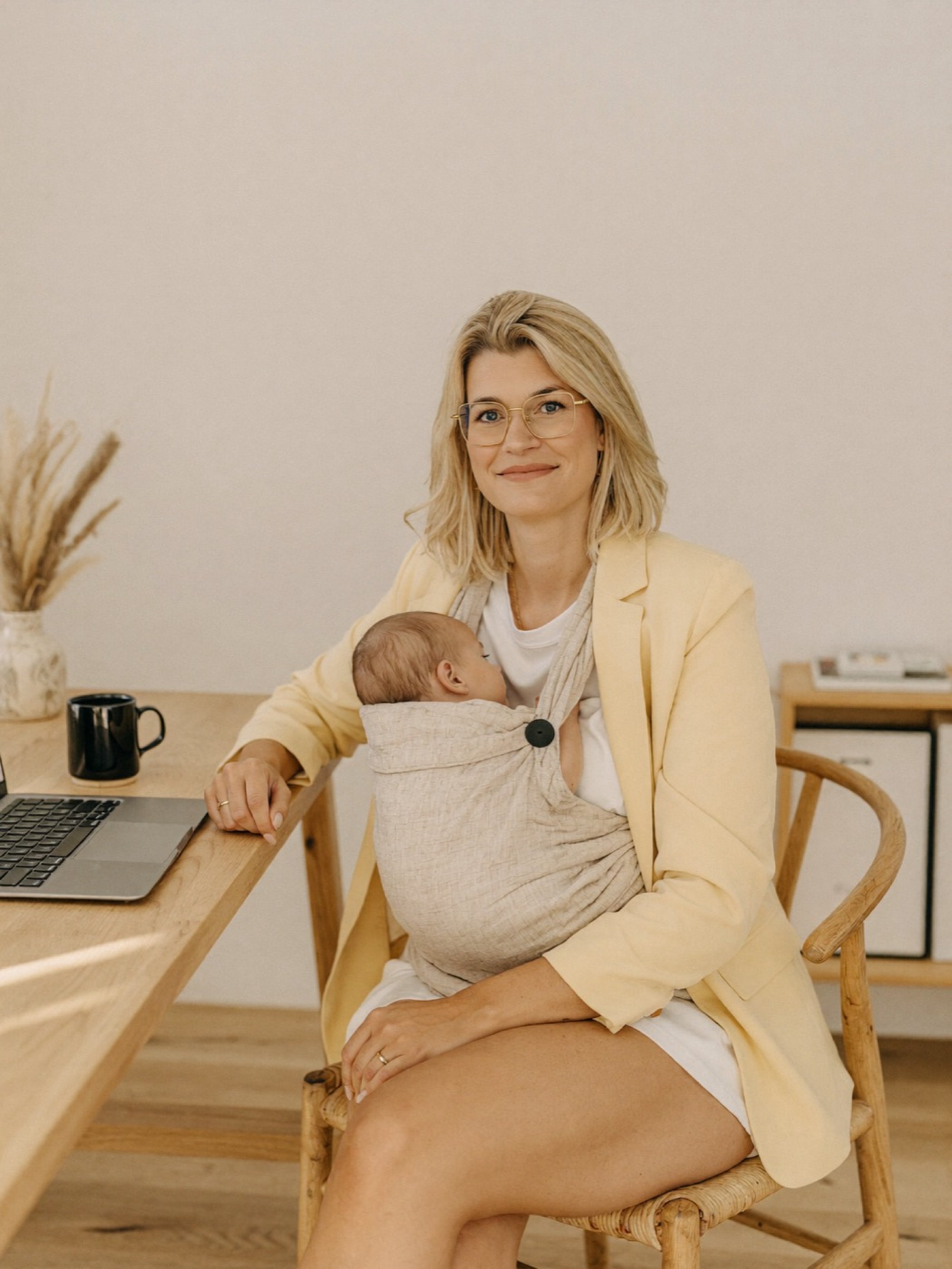 Sina am Schreibtisch mit Laptop, das Baby im Tragetuch
