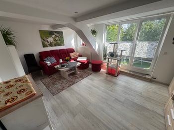 Wohnzimmer mit rotem Sofa und Balkontür