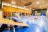 Kinder spielen in einer Sporthalle an verschiedenen Stationen mit Turnmatten, Bänken und einer Holzrutsche.