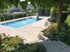 Moderner Swimmingpool mit Steinterrasse, gemauerter Böschung und Gartenbepflanzung vor einer Hügellandschaft.