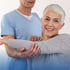 
A therapist assists a smiling woman with arm exercises.