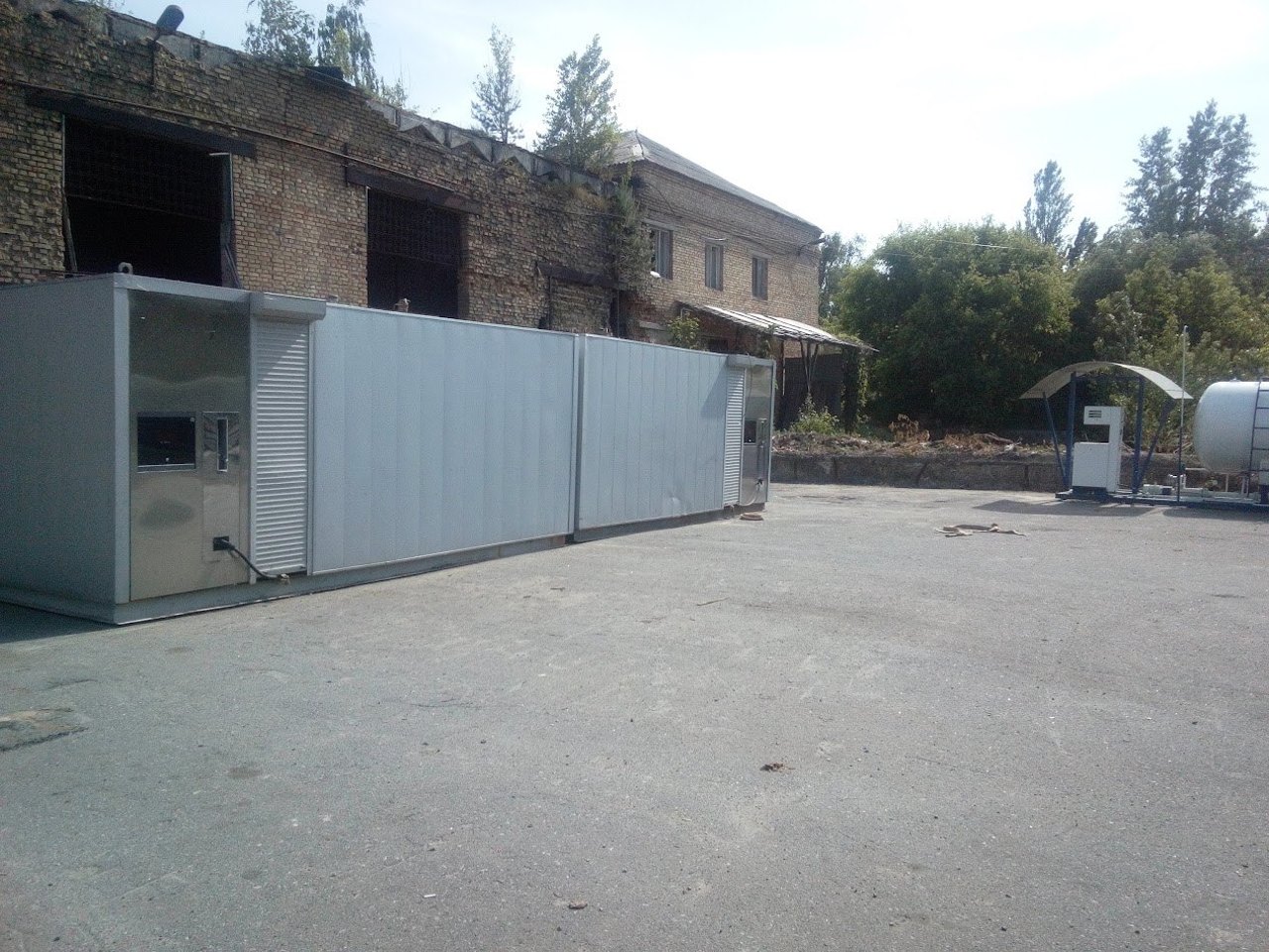 Повноцінна контейнерна АЗС у габаритах 20-футового контейнера з роздавальними вікнами по краях. На тлі — окремий заправний острівець із резервуаром.