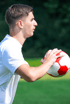 Ein junger Mann im weißen T-Shirt hält einen rot-weißen Fußball bereit zum Einwurf.