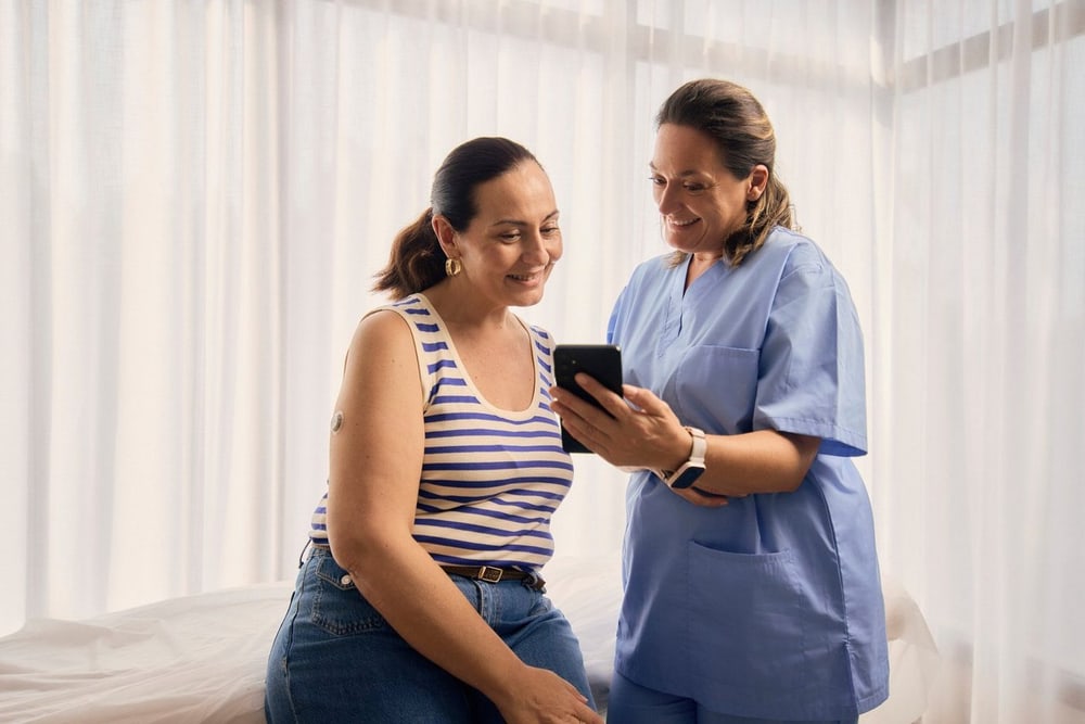 Beraterin erklärt einer Kundin die Dexcom Flex App auf dem Smartphone