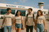 Vier junge Leute in OCEVOO T-Shirts gehen vor dem "Mikonos Airport" Gebäude.