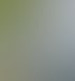 Porträt einer lächelnden Frau mit Brille, kurzem blondem Haar und hellblauem Hemd vor einem unscharfen Außenhintergrund.