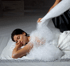Woman lying on her stomach, covered in white foam bubbles, as a person applies more foam from above.