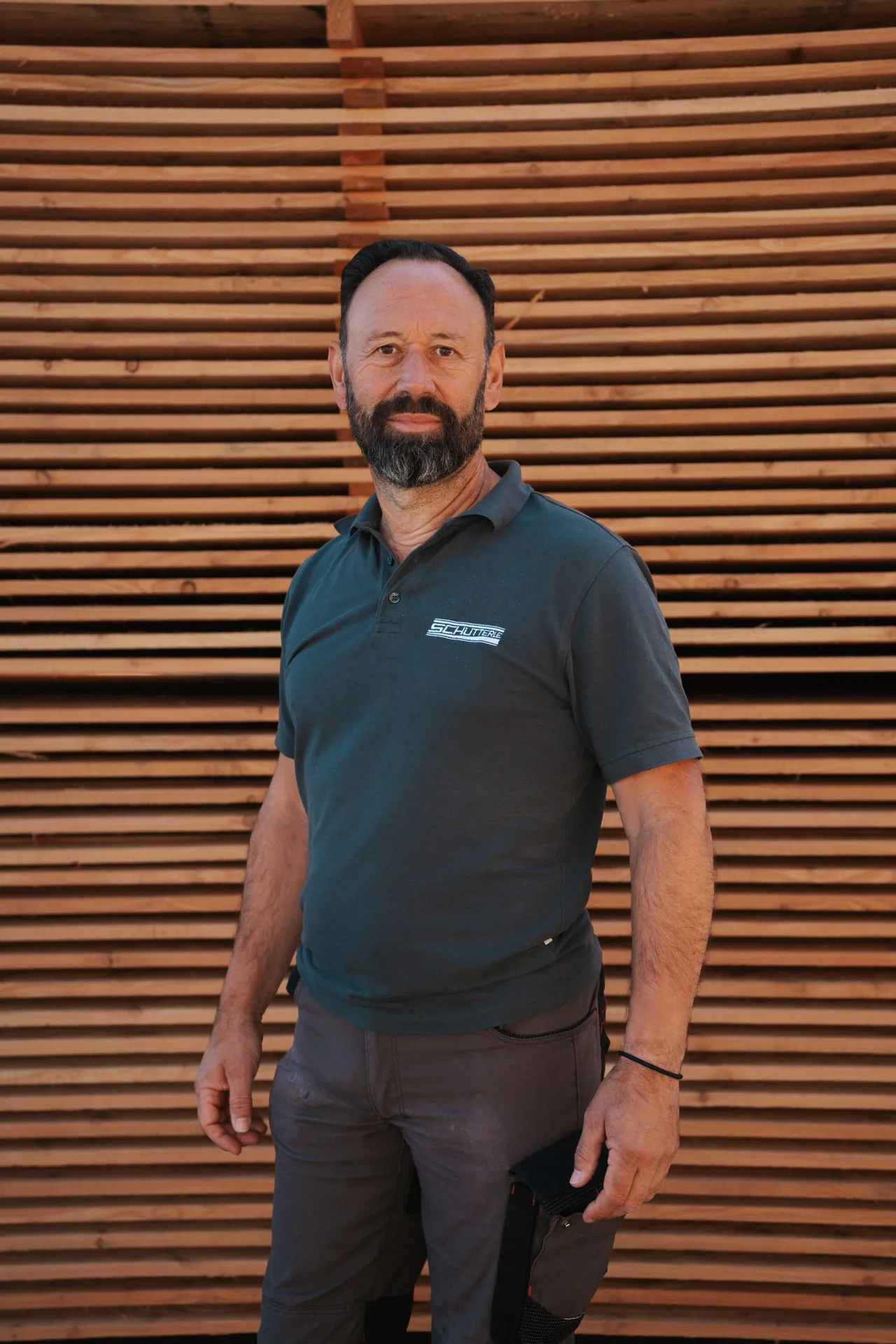 Der Inhaber von Holz Schütterle vor einer Holzwand