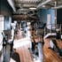 Fitnessstudio mit Crosstrainern und Laufbändern, Holzboden und Wandbild einer Laufbahn.