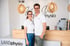 Ein lächelndes Team von LANDphysio steht vor dem Empfangstresen unter modernen Kugelleuchten in der Praxis.