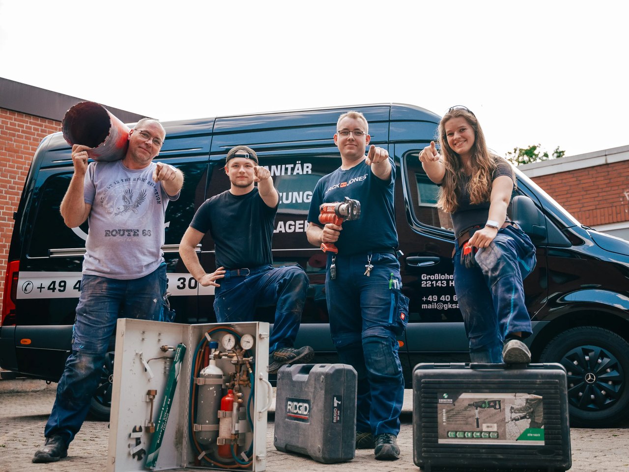 Team der G+K Sanitärtechnik mit Ausrüstung vor den Firmenfahrzeugen in Hamburg