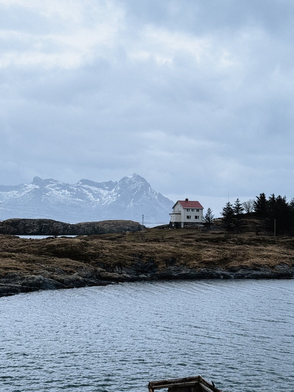 Bucht mit Schneebergen und weißem Haus