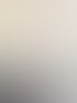 Eine lächelnde Frau mit Brille und hellblauem Hemd lehnt sich an einen Stuhl.