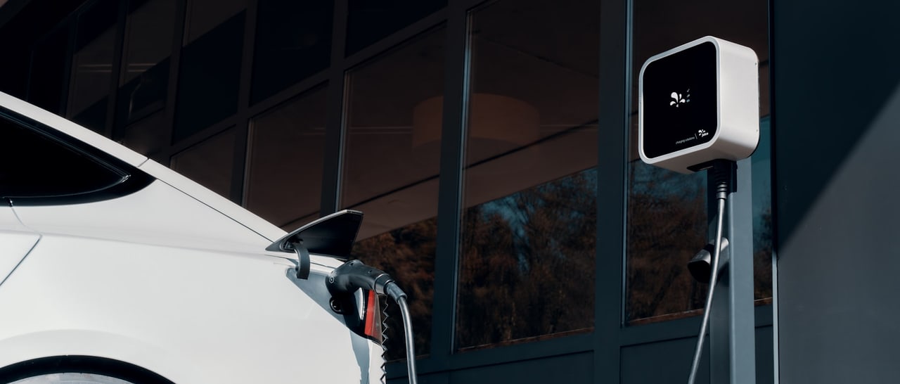 White electric car charging from a wall-mounted EV charger outside a Laguna Niguel home
