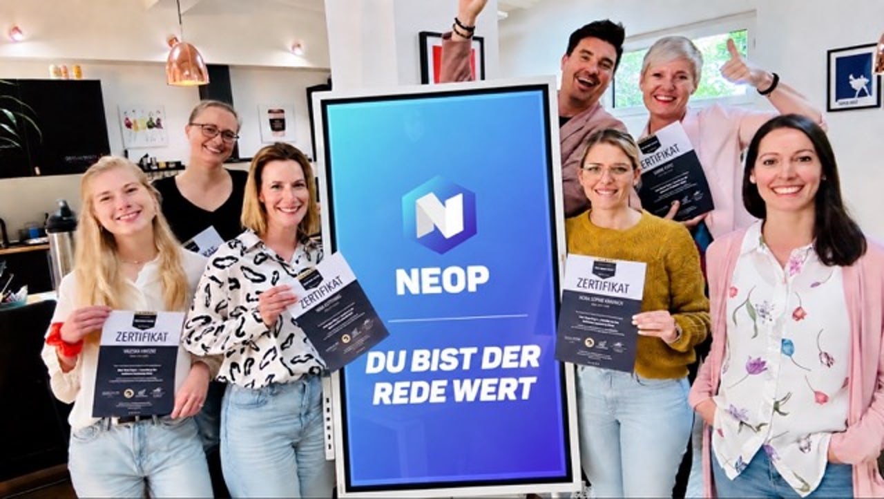 Teilnehmerinnen halten Zertifikate und ein NEOP-Plakat „Du bist der Rede wert“